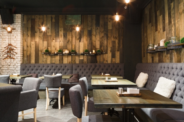 A well-lit restaurant interior has a distinct style with wood paneling and green potted plants.
